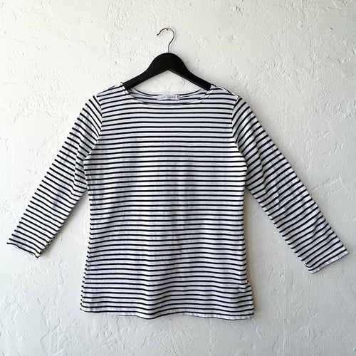 Black and white striped long-sleeve shirt on a hanger against a white wall