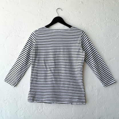 Black and white striped shirt on a hanger against a white wall as viewed from the back