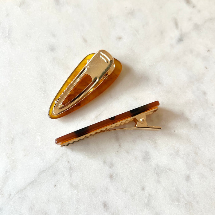 Two hair clips on a marble surface