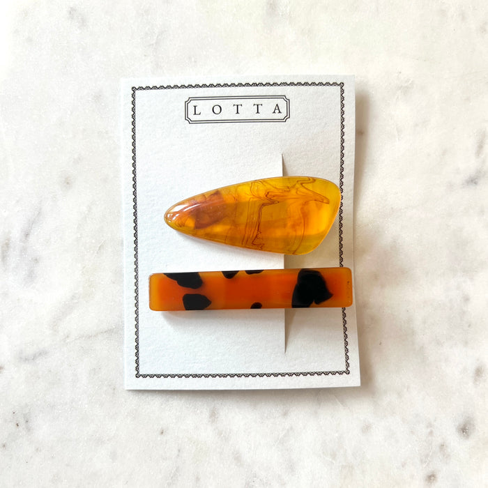 Two tortoiseshell patterned hair clips on a 'Lotta' branded card against a marble background.