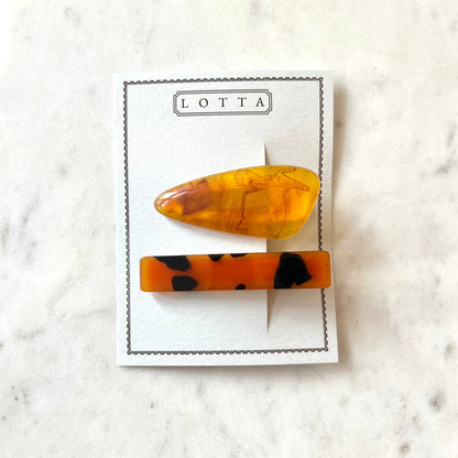 Two tortoiseshell patterned hair clips on a 'Lotta' branded card against a marble background.