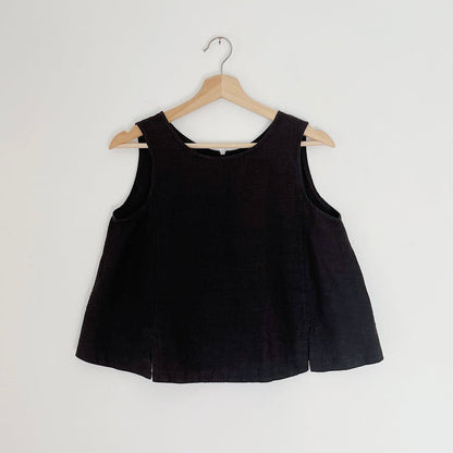 Cropped black linen tank top displayed on a wooden hanger against a white background.