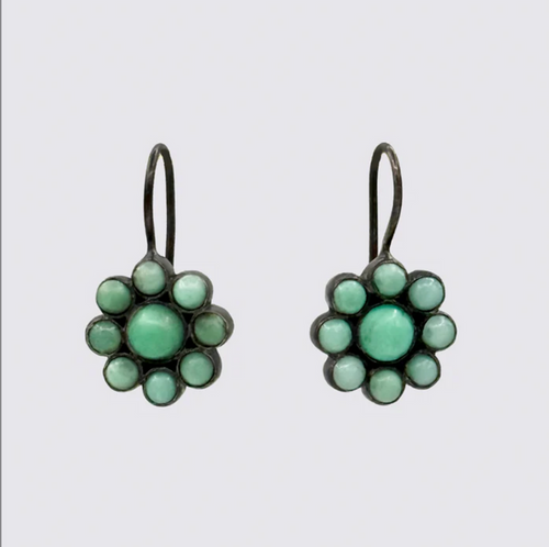 Pair of flower-shaped earrings with green gemstones on a light gray background
