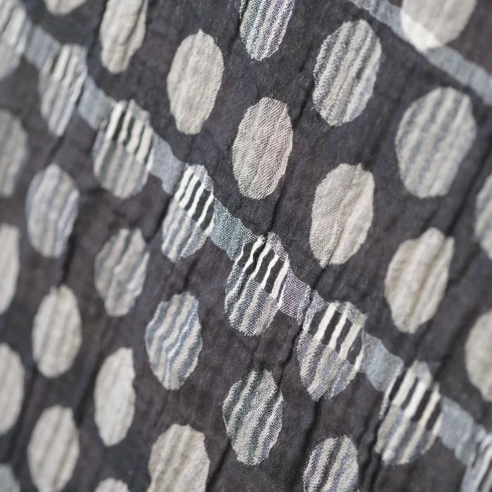 Close-up detail of the Létol Coline Scarf in Noir Gris, showing the Jacquard-woven texture of the polka dot side — large oatmeal, beige, and light grey dots with subtle internal stripe detailing on a deep charcoal ground, highlighting the dimensional woven texture and tonal variation between dots