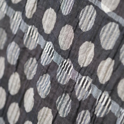 Close-up detail of the Létol Coline Scarf in Noir Gris, showing the Jacquard-woven texture of the polka dot side — large oatmeal, beige, and light grey dots with subtle internal stripe detailing on a deep charcoal ground, highlighting the dimensional woven texture and tonal variation between dots