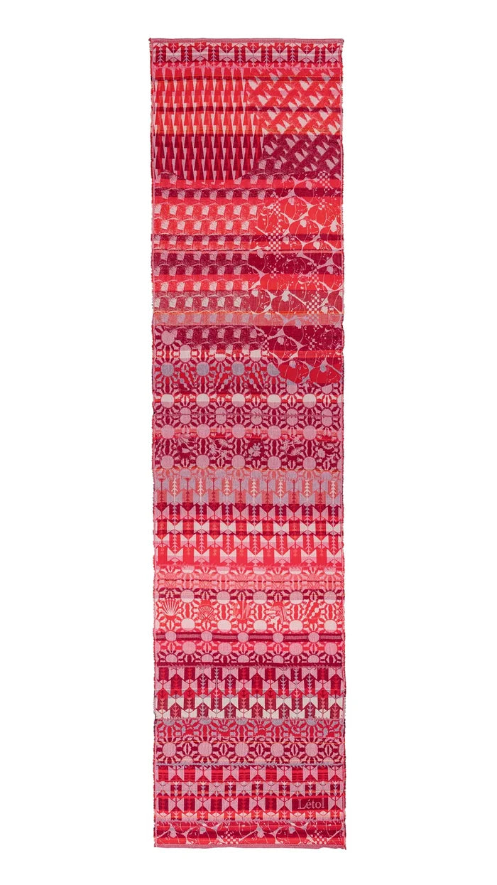 Létol Come Scarf in Red Gala, laid flat and fully extended against a white background, showing the full length of the scarf with multiple distinct horizontal bands of Jacquard-woven patterns in red, cranberry, pink, and chalk tones — including geometric arrow motifs, floral rosette rows, diagonal houndstooth, and medallion repeats — with a small woven Létol label visible at the lower border