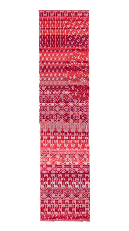 Létol Come Scarf in Red Gala, laid flat and fully extended against a white background, showing the full length of the scarf with multiple distinct horizontal bands of Jacquard-woven patterns in red, cranberry, pink, and chalk tones — including geometric arrow motifs, floral rosette rows, diagonal houndstooth, and medallion repeats — with a small woven Létol label visible at the lower border
