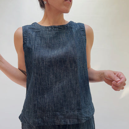 Person wearing a sleeveless denim top against a plain background