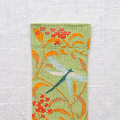 Close-up of the ankle portion of the socks with floral and dragonfly design on a light background