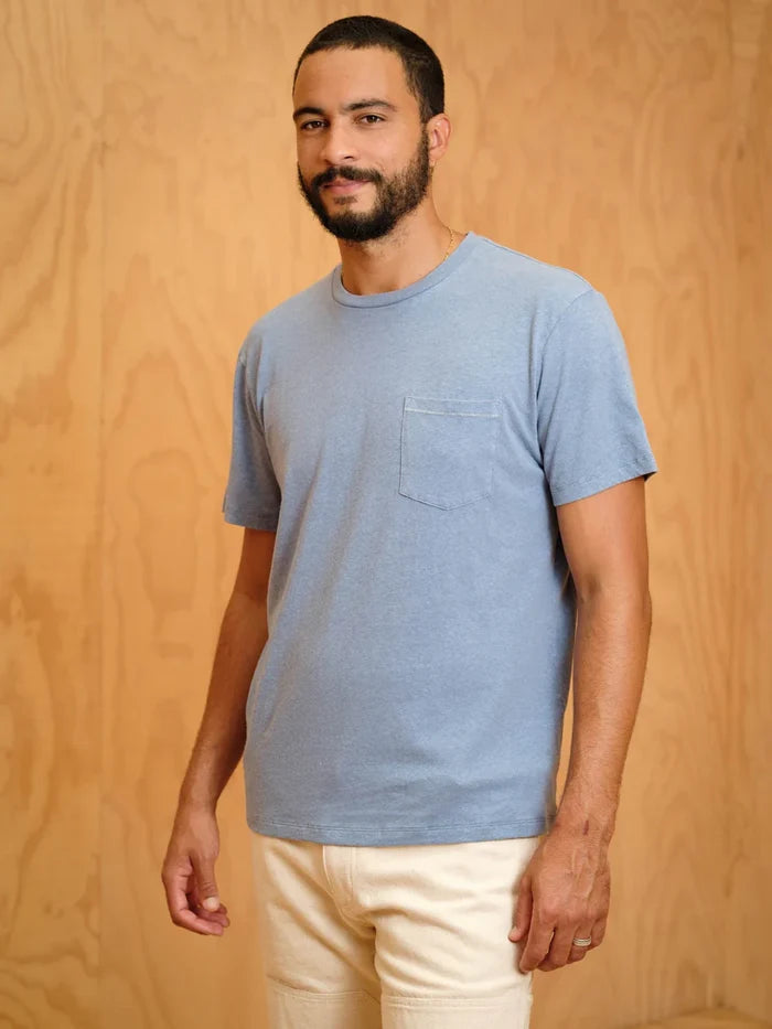 Man wearing a blue t-shirt with a pocket against a wooden background