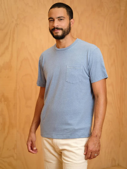 Man wearing a blue t-shirt with a pocket against a wooden background