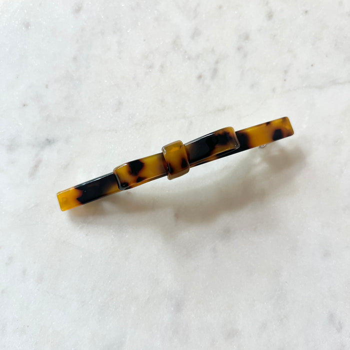 Tortoiseshell patterned hair clip on a white marble background