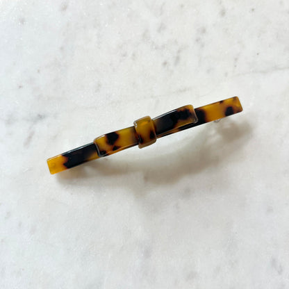 Tortoiseshell patterned hair clip on a white marble background