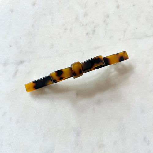 Tortoiseshell patterned hair clip on a white marble background