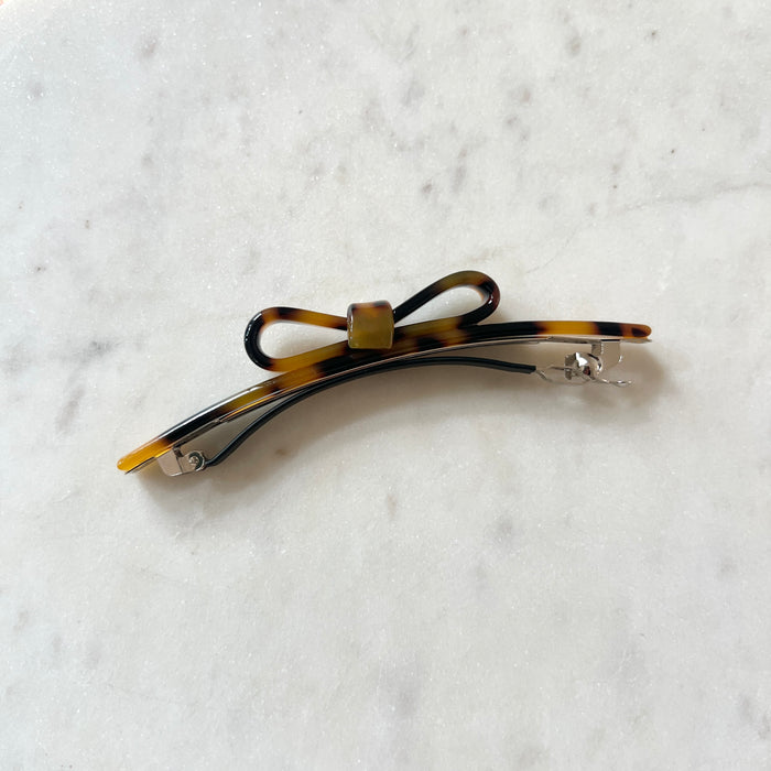 Tortoiseshell bow hair clip on a white marble background