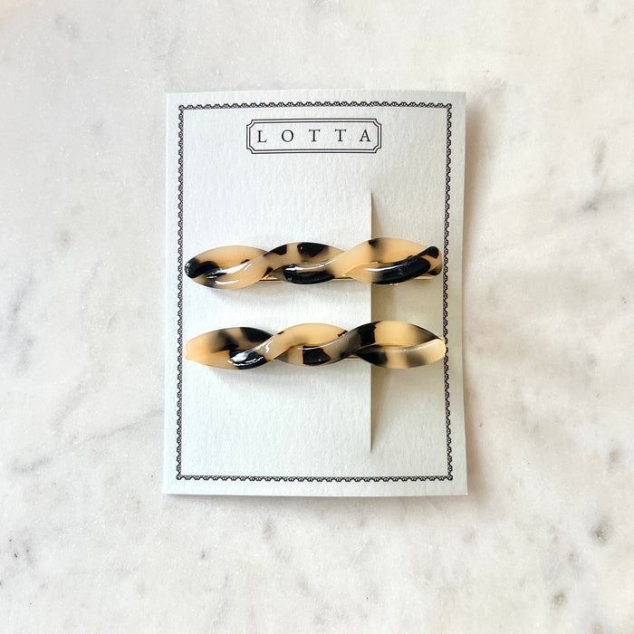 Two tortoiseshell hair clips on a 'Lotta' branded card against a marble background