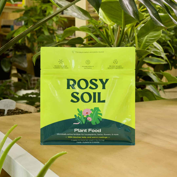 Rosy Soil | Plant Food | A lime green package with text "Boost benficial nutrients + Micrbes, No pest moss or synthetics, we love natural and upcycled ingredients" "Rost Soil, Plant Food, Microbially active fertilizer for houseplants, herbs, flowers, & more. With biocar, kel, and worm castings. 2 quarts, 2lbs, feeds 6 plants for 3 months"