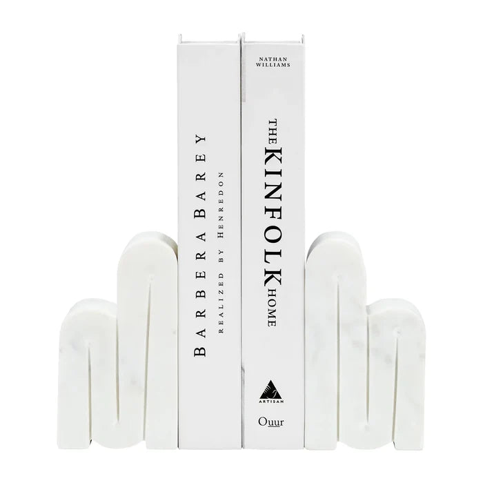 Swirly Marble Bookends | White marble bookends in a swirling pattern, holding up two books: BarberaBarey Realized by Henredon, and The Kinfolk Home by Nathan Williams".