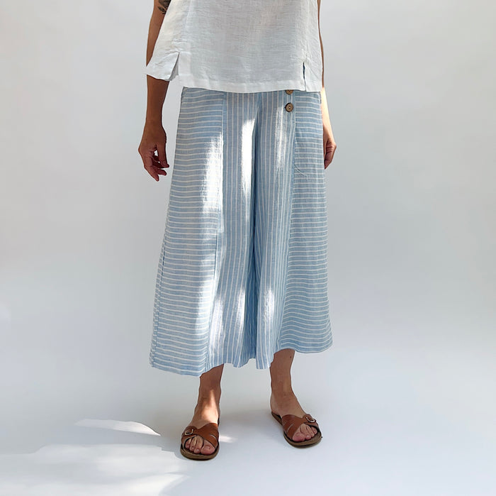 Person wearing light blue striped pants and white top on a plain background