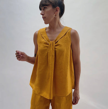 Front view of the Sailor Tank in Turmeric by Yuvita, showing the V-neckline with gathered twist detail, sailor collar, and relaxed linen silhouette in golden turmeric yellow, styled with matching linen wide-leg pants