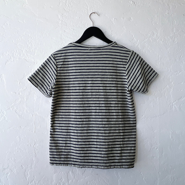 Green and black striped t-shirt on a hanger against a white wall, viewed from behind
