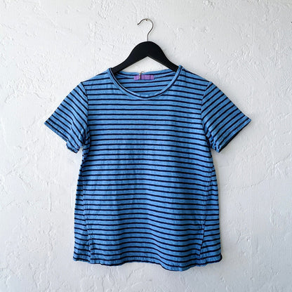 Blue and navy striped t-shirt on a hanger against a white wall