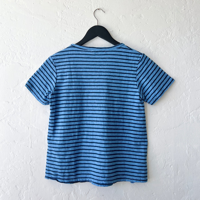 Blue and navy striped t-shirt on a hanger against a white wall, viewed from the back