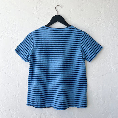Blue and navy striped t-shirt on a hanger against a white wall, viewed from the back