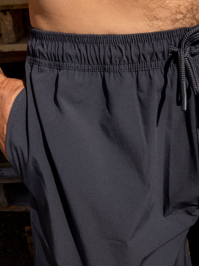 Close-up detail of the Mollusk Surf Shop Stretch Vacation Trunks in Navy, showing elastic waistband, navy drawstring, and smooth quick-dry nylon fabric