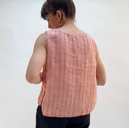 Person wearing a pink sleeveless shirt with vertical stripes against a plain background, viewed from the back