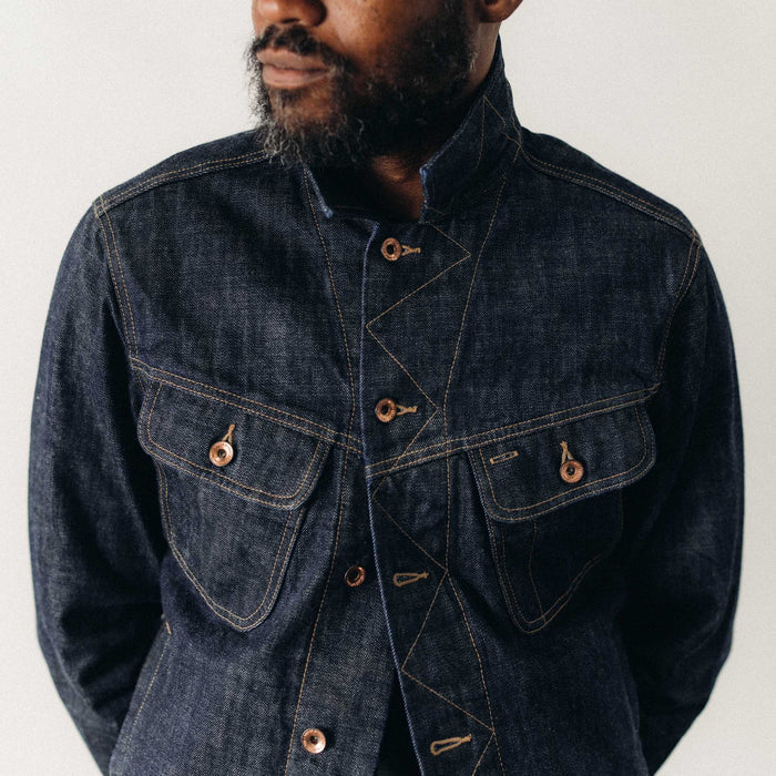 Close-up of a man wearing The Long Haul Jacket in Rinsed Organic Selvedge by Taylor Stitch, highlighting the chest pocket detail, copper hardware, and contrast stitching on the dark indigo denim.