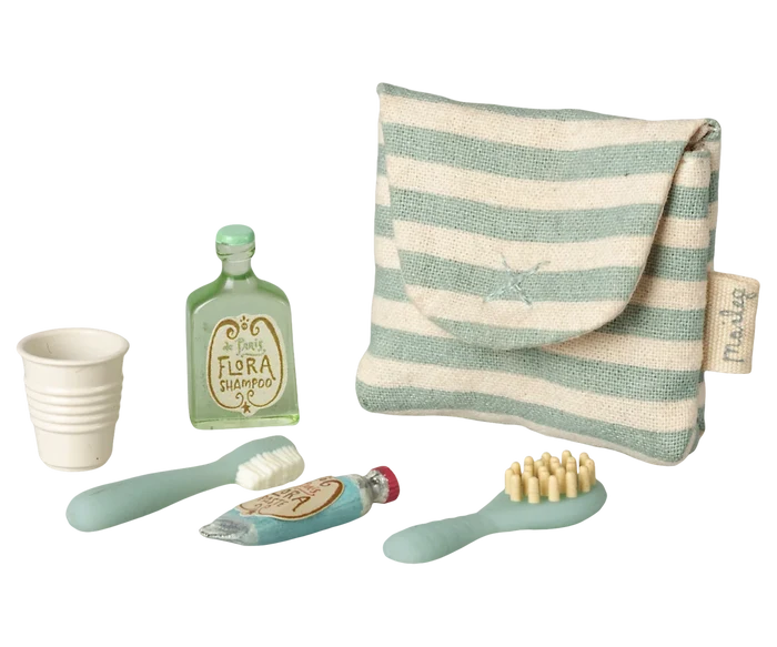 Maileg Toothbrush Set in Blue Striped Bag — angled view of the blue striped Maileg toiletry bag alongside miniature accessories including a Flora Shampoo bottle, ribbed cup, toothbrush, toothpaste tube, and hairbrush