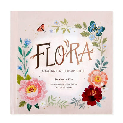 A light pink book with a floral and butterfly pattern. Rose gold foiled text reads "Flora a botanical pop-up book by Yoojin Kim, illustration by kathryn selbert, text by Nicole Yen.